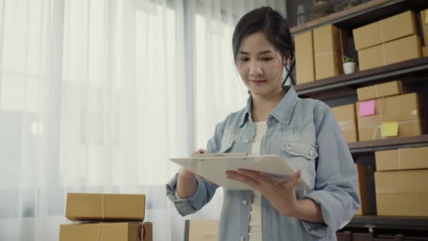 美丽聪明的亚洲年轻企业家女老板 检查产品的股票 并写在剪贴板上工作在家里 小企业主在家里的办公室概念 — 图库视频影像