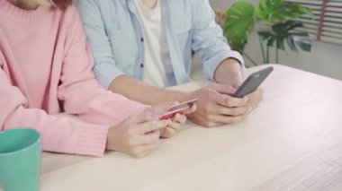 Genç Asyalı aile çift haber tartışmaya veya online alışveriş birlikte masanın üzerinde evde hafta sonu birlikte, ciddi erkek ve kadın için yeni satış teklifleri web arama tarama oturan yapıyor smartphone kullanarak.