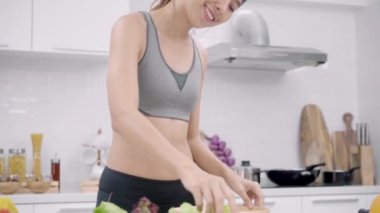 Genç Asyalı kadın mutlu duygu dans, müzik ve spor giyim evde mutfakta beslenme bol salata yapmak için dinle. Yaşam tarzı kadın sağlıklı gıda kavramı yapma.