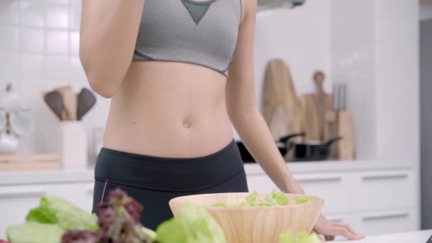 年轻的亚洲妇女喝橙汁做沙拉在厨房 美丽的女性在运动服装使用有机水果和蔬菜制作健康食品独自在家 健康食品理念 — 图库视频影像