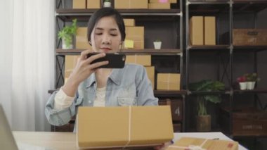 Güzel akıllı Asya genç girişimci iş kadın KOBİ ürün evde çalışan hisse senedi tarama qr kod üzerinde kontrol sahibi. Küçük işletme sahibi, ev ofis kavramı.