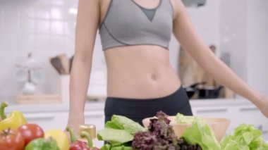 Genç Asyalı kadın güzel kadın kullanım sebze salatası evde fit vücut için hazırlanıyor mutfakta görünümlü tarifi için tablet kullanırken salata sağlıklı yemek yapma. Sağlıklı gıda kavramı.