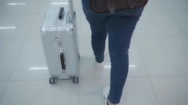 Yavaş hareket - birçok bagajlı terminal salonunda Uluslararası Havaalanı kalkış kapısında yatılı uçuşa giderken yürüme arabası veya sepeti kullanarak mutlu Asyalı kadın.