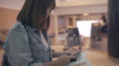 Kullanarak ve uçağının kalkış kapısı uluslararası havaalanında beklerken onun smartphone terminal salonunda kontrol mutlu Asyalı kadın. Kadınlar Havaalanı kavramında mutlu.