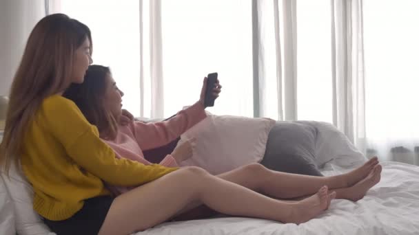 美しい若いアジア女性 Lgbt レズビアン幸せなカップル ベッド抱擁の上に座って Selfie 一緒に寝室を取って電話を使用して Lgbt レズビアン カップル一緒に室内の概念 素敵な時間を過ごす家 — ストック動画