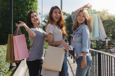 Genç Asyalı kadın ellerinde alışveriş torbaları ile açık bir pazarda alışveriş grubudur. Genç Asyalı kadınlar sıcak güneş ışığı altında alışveriş torbasında marifetlerini göster. Grup açık alışveriş kavramı.