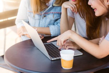 Grup kadınların güzel akıllı iş serbest Asya smart casual giyim yaratıcı ofis veya kafeterya masada otururken dizüstü bilgisayar ya da bilgisayar üzerinde birlikte çalışma.