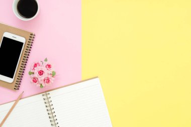 Ofis Masası adlı kullanıcının alanı - düz çalışma beyaz boş defter sayfası, kahve fincanı ve sahte telefon pastel arka plan üzerinde bir çalışma alanının en iyi görünümü yatırın. Pastel pembe sarı renk arka plan boşluk kavramı.