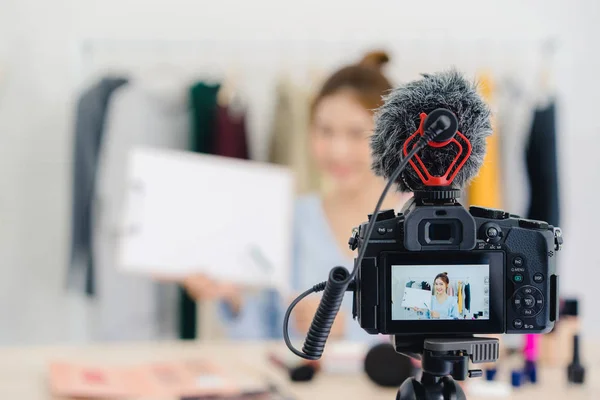 Beauty blogger present beauty cosmetics sitting in front camera for recording video. Beautiful asian woman use cosmetics while review make up tutorial broadcast live video to social network by internet.