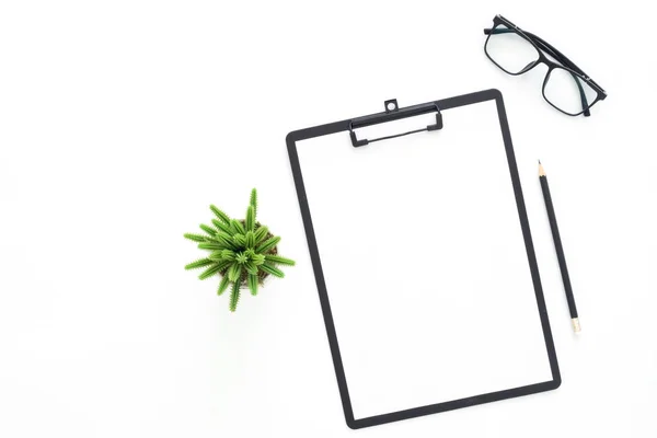 Creative flat lay photo of workspace desk. Top view office desk with glasses, pencil, blank clipboard and plant on white color background. Top view with copy space, flat lay photography.