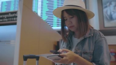 Kullanarak ve uçağının kalkış kapısı uluslararası havaalanında beklerken onun smartphone terminal salonunda kontrol mutlu Asyalı kadın. Kadınlar Havaalanı kavramında mutlu.