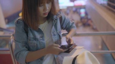 Kullanarak ve uçağının kalkış kapısı uluslararası havaalanında beklerken onun smartphone terminal salonunda kontrol mutlu Asyalı kadın. Kadınlar Havaalanı kavramında mutlu.