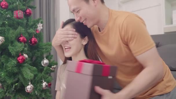 アジア カップル男のクリスマス フェスティバルで自宅リビング ルームで彼のガール フレンドにクリスマス プレゼントを与えます ライフ スタイルの女と男の幸せな夏を祝うクリスマスと新しい年の概念 — ストック動画