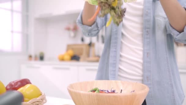 スローモーション 有機野菜たっぷり栄養フィット体自宅のサラダを準備する台所 カジュアルな使用で美しい女性でサラダ健康食品を作る若いアジア女性 健康食品のコンセプト — ストック動画