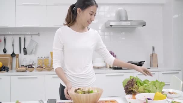 有機野菜たっぷり栄養フィット体自宅のサラダを準備する台所 カジュアルな使用で美しい女性でサラダ健康食品を作る若いアジアの女性 健康食品のコンセプト — ストック動画