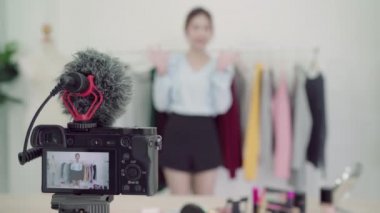 Asya moda kadın blogger online etki unsuru holding alışveriş torbaları ve giysi bir sürü yeni moda video yayını kaydetmek için giysi raf üzerinde canlı video evde sosyal ağ Internet tarafından için.