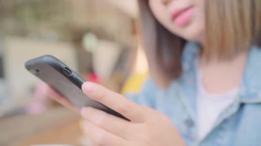 Kafede masada otururken konuşma, okuma ve manifatura için Smartphone kullanarak iş serbest Asyalı kadın. Kahve dükkanı concepts çalışma yaşam tarzı zeki güzel kadınlar.