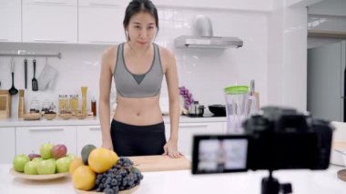 Nasıl elma suyu video onun abone, kadın için organik meyve elma suyu tek başına evde yapma kullanın yapmak için kayıt kamera kullanarak Blogger Sportif Asyalı kadın. Sağlıklı gıda kavramı.
