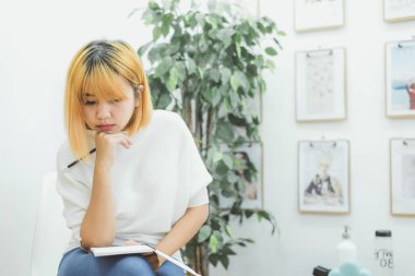 Asyalı kadın yazma alışveriş mutfak tezgahı evde ve okuma kalem tarafından Not Defteri'nde listeler ve alışverişe için tüm malzemeyi hatırlamaya çalışır. Yaşam tarzı kadın evde kavramı relax.