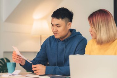Genç Asyalı Çift yönetmek maliye, dizüstü bilgisayar ve hesap makinesi modern ev kullanarak banka hesaplarının incelenmesi vurguladı. Kadın ve evrak birlikte, ödeme vergi online yapan erkek.