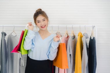 Asya moda kadın blogger online etki unsuru holding alışveriş torbaları ve giysi bir sürü yeni moda video yayını kaydetmek için giysi raf üzerinde canlı video evde sosyal ağ Internet tarafından için.