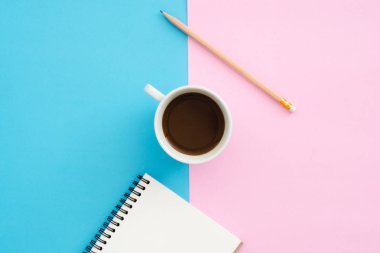 Yaratıcı düz Fotoğraf çalışma masası yatıyordu. Üstten görünüm ofis masası mavi pembe renkli arka plan üzerinde kalem, defter ve kahve Kupası ile. Kopya alanı, düz yatıyordu fotoğraf ile üstten görünüm.