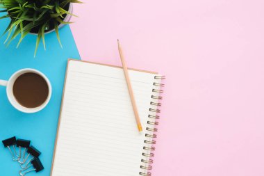 Yaratıcı düz Fotoğraf çalışma masası yatıyordu. Üstten görünüm ofis masası mavi pembe renkli arka plan üzerinde bitki, kalem, defter ve kahve Kupası ile. Kopya alanı, düz yatıyordu fotoğraf ile üstten görünüm.