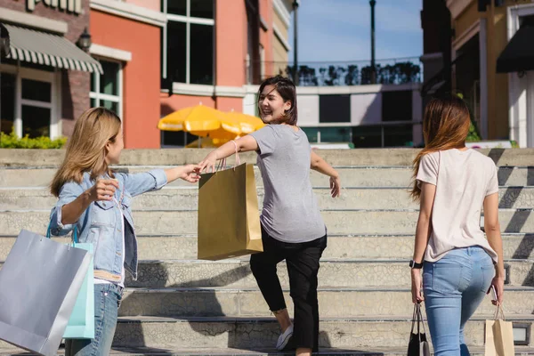 Genç Asyalı kadın ellerinde alışveriş torbaları ile açık bir pazarda alışveriş grubudur. Genç Asyalı kadınlar sıcak güneş ışığı altında alışveriş torbasında marifetlerini göster. Grup açık alışveriş kavramı.