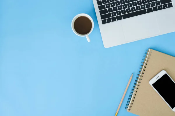 Office desk working space - Flat lay top view mockup photo of working space with laptop, smartphone, coffee and stationary on blue pastel background. Pastel blue color copy space working desk concept.