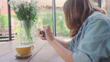 Kadın blogger yeşil çay bardağı Cafe telefonu ile fotoğraf çekmek. Bir genç kadın alarak fotoğraf kahve çay Smartphone, yemek Mobil kamera ile fotoğraf çekimi.