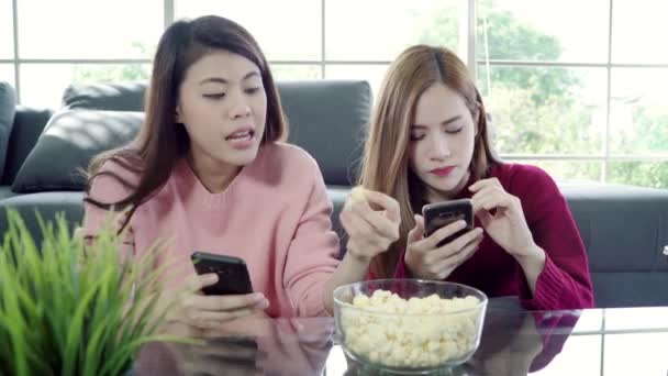 亚洲女性在家里的客厅里使用智能手机和吃爆米花 一群室友朋友躺在沙发上享受有趣的时刻 生活方式的女性放松在家里的概念 — 图库视频影像