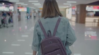 Birçok bagajlı terminal salonunda Uluslararası Havaalanı kalkış kapısında yatılı uçuşa giderken yürüme arabası veya sepeti kullanarak mutlu Asyalı kadın. Kadınlar Havaalanı kavramında mutlu.