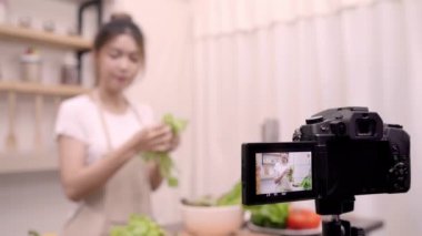 Blogger Asyalı kadın nasıl salata sağlıklı gıda için onun abone, kadın kullanımı organik sebze salata evde fit vücut için hazırlama video yapmak için kayıt kamerayı kullanarak. Sağlıklı gıda kavramı.