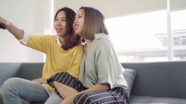 Lezbiyen çift evde oturma odasında gülmek Tv izlerken, tatlı çift kanepede yatarken komik an zevk Asya ne zaman evde dinlenin. Yaşam tarzı çift evde kavramı relax.