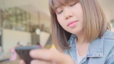 Kafede masada otururken konuşma, okuma ve manifatura için Smartphone kullanarak iş serbest Asyalı kadın. Kahve dükkanı concepts çalışma yaşam tarzı zeki güzel kadınlar.