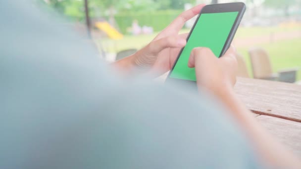 年轻的亚洲妇女使用黑色手机设备与绿色屏幕 亚洲妇女拿着智能手机 滚动页面 而坐在咖啡馆 色度键 — 图库视频影像