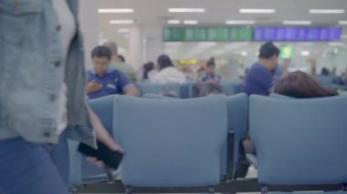 Kullanarak ve onun smartphone uçağının kalkış kapısı uluslararası havaalanında beklerken terminal Salonu sandalyede oturan süre kontrol mutlu Asyalı kadın. Kadınlar Havaalanı kavramında mutlu.