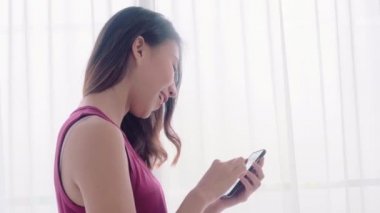 Genç Asyalı kadınlar lezbiyen mutlu çift yatak odalı evde, sosyal medya kontrol smartphone kullanarak aşk an rahat zaman pencerenin iken yakınındaki tadını çıkarın. Yaşam tarzı Lgbt çift birlikte kapalı kavramı.