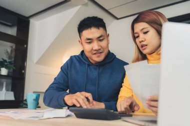 Genç Asyalı Çift yönetmek maliye, dizüstü bilgisayar ve hesap makinesi modern ev kullanarak banka hesaplarının incelenmesi. Kadın ve erkek birlikte, ödeme vergi online defter PC evrak işi.