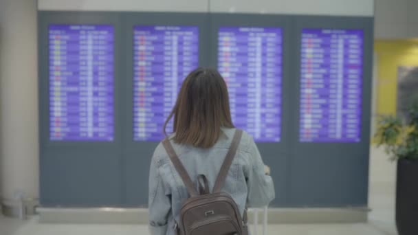 愉快的亚洲妇女看着信息板检查她的航班与行李在候机楼在国际机场的登机口 生活中的女人快乐在机场概念 — 图库视频影像