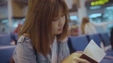 Mutlu Asyalı kadın uçağının kalkış kapısı uluslararası havaalanında beklerken terminal Salonu sandalyede oturan arıyorum. Yaşam tarzı kadın Havaalanı kavramında mutlu.