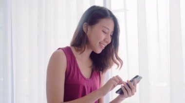 Genç Asyalı kadınlar lezbiyen mutlu çift yatak odalı evde, sosyal medya kontrol smartphone kullanarak aşk an rahat zaman pencerenin iken yakınındaki tadını çıkarın. Yaşam tarzı Lgbt çift birlikte kapalı kavramı.