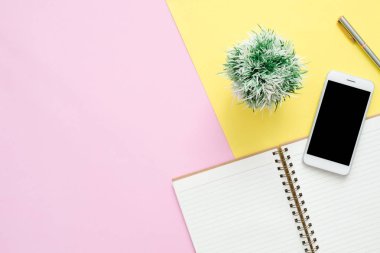 Ofis Masası adlı kullanıcının alanı - düz çalışma beyaz boş defter sayfası, ağaç bitki ve sahte telefon pastel arka plan üzerinde bir çalışma alanının en iyi görünümü yatırın. Pastel pembe sarı renk arka plan boşluk kavramı.