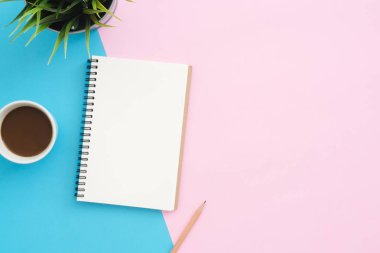 Yaratıcı düz Fotoğraf çalışma masası yatıyordu. Üstten görünüm ofis masası mavi pembe renkli arka plan üzerinde bitki, kalem, defter ve kahve Kupası ile. Kopya alanı, düz yatıyordu fotoğraf ile üstten görünüm.