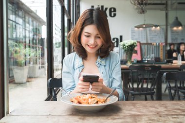 Kadın blogger telefonunu restoranda öğle fotoğraf çekme. Spagetti yemek yemek Mobil kamera ile fotoğraf çekme Smartphone cep telefonu ile bir genç kadın alarak fotoğraf.