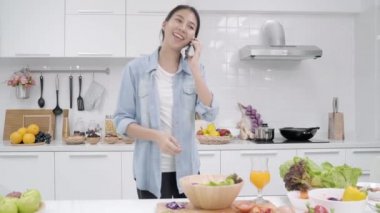 Salata sağlıklı yemek yapma ve smartphone mutfakta güzel kadın kullanımı organik sebze salatası evde hazırlamak konuşurken Genç Asyalı kadın. Yaşam tarzı kadın evde kavramı relax.