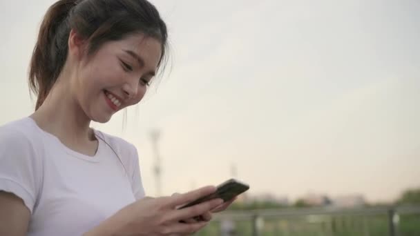 在市中心的街道上散步时 愉快的亚洲旅游博主女士在智能手机上使用触摸屏技术 生活方式背包旅游旅游度假的概念 — 图库视频影像