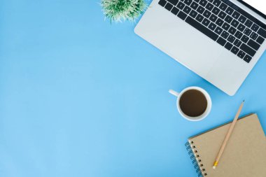 En az çalışma alanı - yaratıcı düz fotoğraf çalışma masası yatıyordu. Üstten Görünüm ofis büro dizüstü bilgisayar, dizüstü bilgisayarlar ve mavi renk arka plan üzerinde kahve fincanı. Kopya alanı, düz yatıyordu fotoğraf ile Üstten Görünüm.