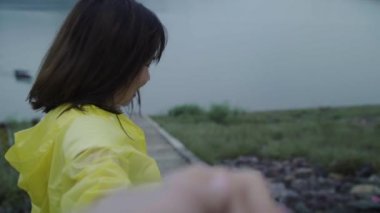 Yavaş hareket - yağmurluk ayakta göl kenarında giyen süre Genç Asyalı kadın duygu mutlu oynarken yağmur. Yaşam tarzı kadın zevk ve yağmurlu günde dinlenmek.