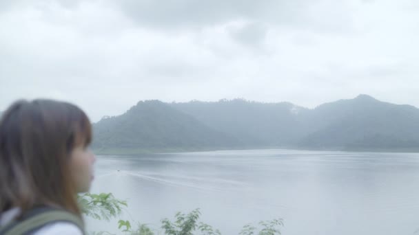 徒步旅行者背包客在徒步探险中感受到在雨天在湖边森林中行走的自由 生活方式女性旅行放松概念 — 图库视频影像